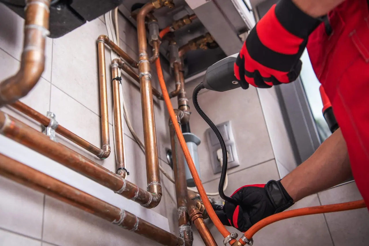 Copper, iron, and black drain pipes exposed in a ceiling cavity