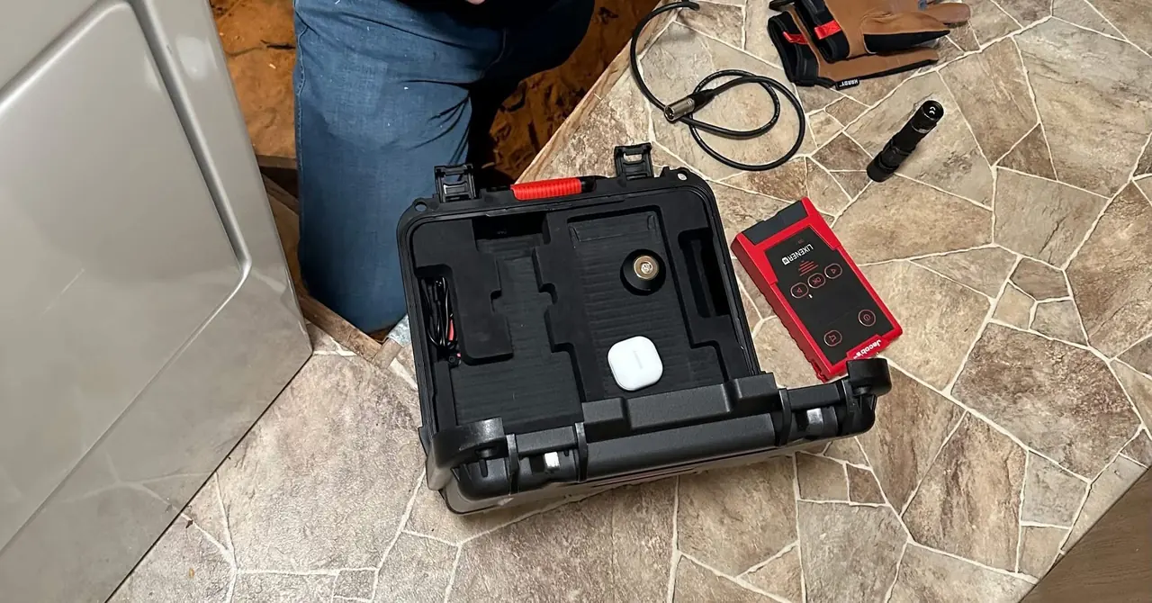 Leak detection equipment case open beside a crawlspace access under a laundry area