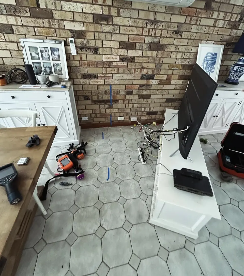 Floor marked with blue tape beside leak detection equipment on a tile floor
