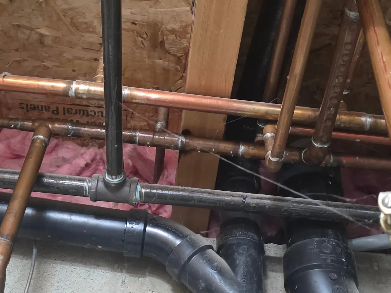 Technician holding a handheld detector against copper water pipes
