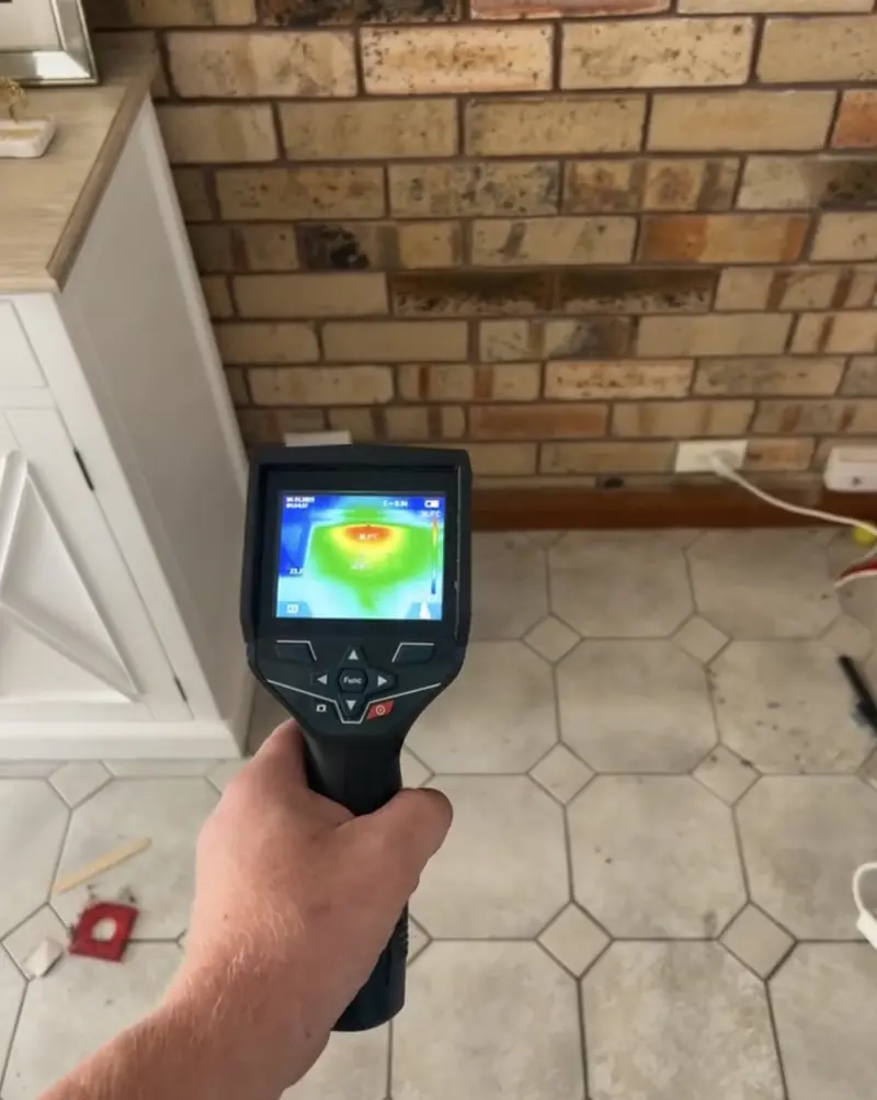 Thermal camera screen showing a cool damp patch low on a brick wall